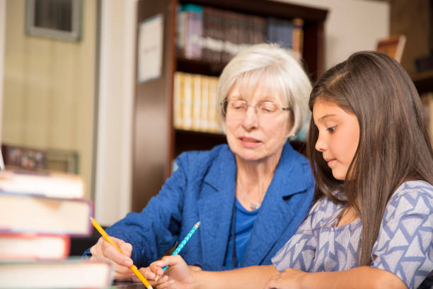 istock Teacher, mentor helps elementary-age schoolgirl with homework. 831728820