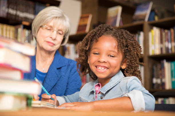 istock Teacher, mentor helps elementary-age schoolgirl with homework. 831729202