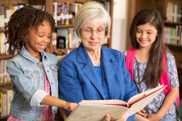 istock Teacher, librarian reads book to elementary students in library or classroom. 831730532