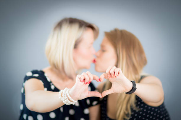 Two women kissing and showing heart shape with their hands, love