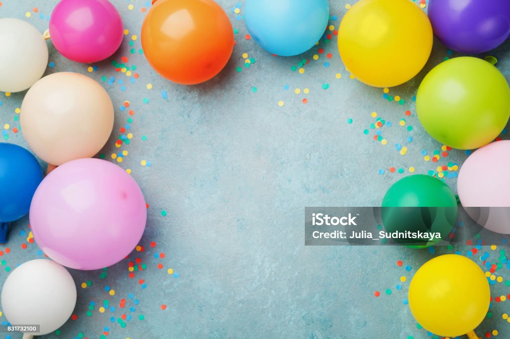 Coloridos globos y confeti en la mesa azul ven. Fondo festivo o fiesta. Tarjeta de felicitación de cumpleaños. - Foto de stock de Celebración - Ocasión especial libre de derechos