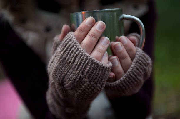 istock Metal mug with hot tea in a hands in a warm cozy mittens 831732136