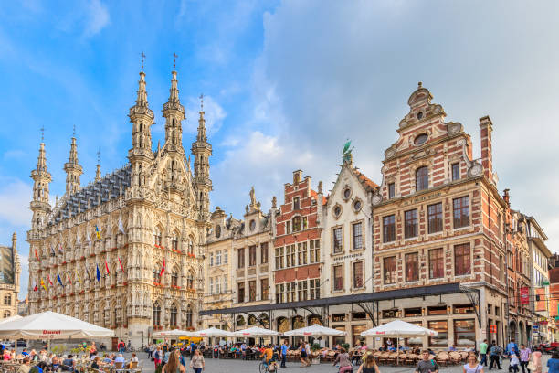 Tourists visiting the Grote Markt, the major town square of Leuven, a famous university city of the Flanders. The beautiful square is bordered by monumental buildings, such as the majestic Town Hall, built between 1439 and 1463 in a Brabantian late-Gothic style. The statues adorning the facades were added in the 19th century to commemorate prominent personalities of the city history.