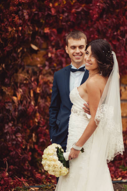 istock Wedding couple on a walk near a wall with red leaves 831736562