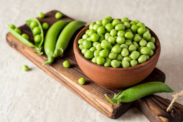 istock Fresh green peas in ceramic bowl on gray stone background 831739354