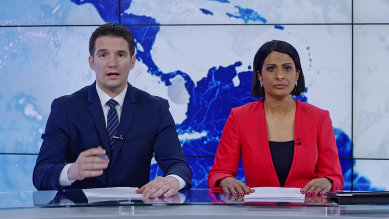 LD Indian anchorwoman and Caucasian anchorman presenting the news