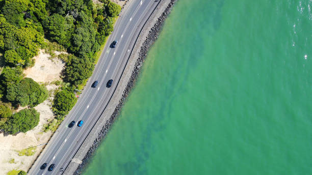 vista aérea em uma estrada que corre ao longo da costa do mar. auckland, nova zelândia. - pacific coast highway - fotografias e filmes do acervo