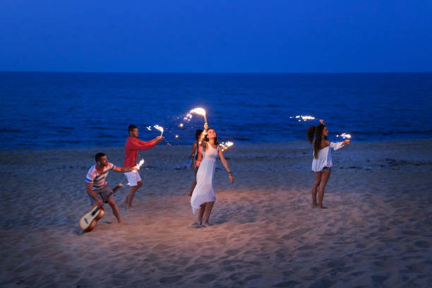 istock Group of people celebrating with flaming torches on beach 831741664