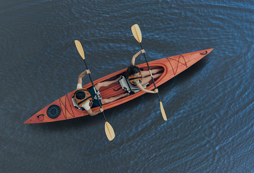 Top view of happy young couple in sea vests sailing a kayak