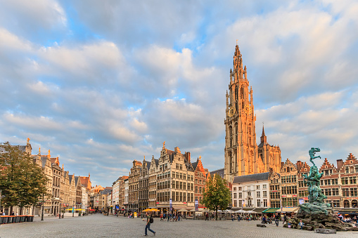 Tourists visiting the Grote Markt, the major town square of Antwerp, in the Flemish Region of Belgium. Among the beautiful ancient buildings, stands out the 123 metres high spire of the Cathedral of Our Lady, a Gothic style church listed in the Unesco World Heritage Site.