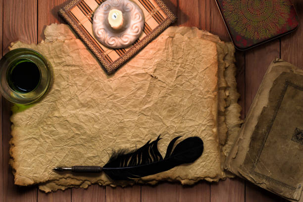 istock vintage feather with paper and ink on table in light of candle 831745220