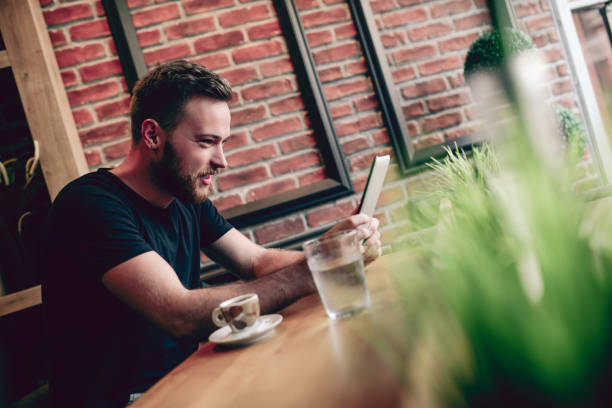 istock Young Smiling Man Watching Funny Videos on Digital Tablet 831748276