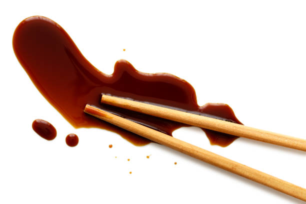 istock Spilled soya sauce on white with wooden chopsticks from above. 831760108