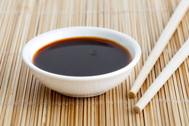 istock Soya sauce in white bowl on bamboo mat with wooden chopsticks. 831760206