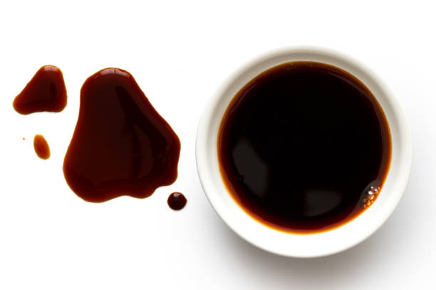 istock Soya sauce in white ceramic bowl isolated on white from above. Spilled soya sauce. 831761670