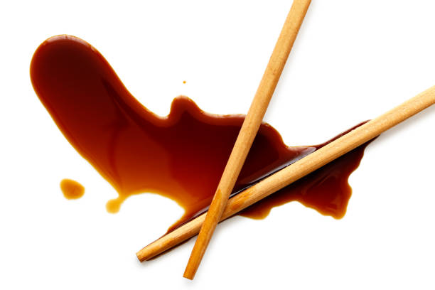 istock Spilled soya sauce on white with wooden chopsticks from above. 831763936