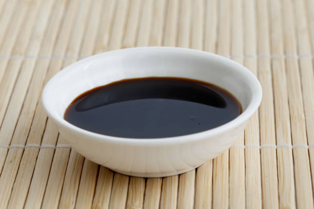 istock Soya sauce in white ceramic bowl isolated on bamboo mat. 831764002