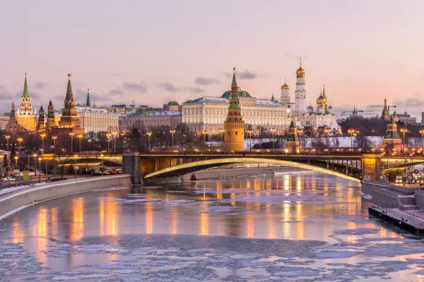 Illuminated Moscow Kremlin and Moscow river in winter morning. Pinkish and golden sky with clouds. Russia