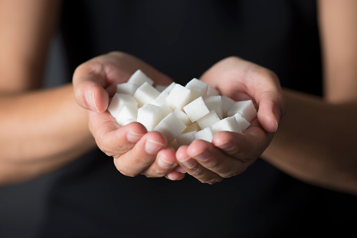 Caucasian female is holding sugar cubes in hand.