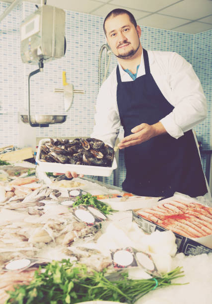 istock Seller holds container of large mussels 831806134