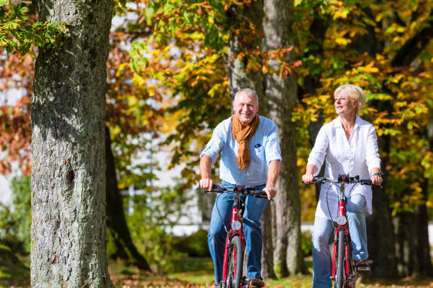 personnes âgées sur les bicyclettes ayant tour dans le parc - tourist senior adult senior couple couple photos et images de collection