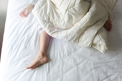 Pies desnudos de una mujer joven en cama blanca photo