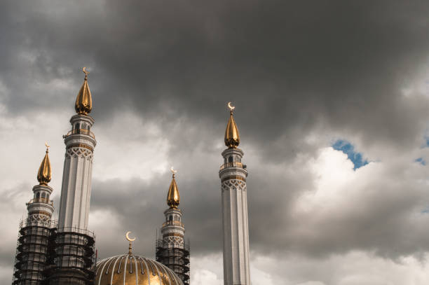 Muslim mosque with Crescent moon on the spire, a historic landmark, the minaret on the background of sky with clouds, cumulonimbus clouds, concept clouds over Islam