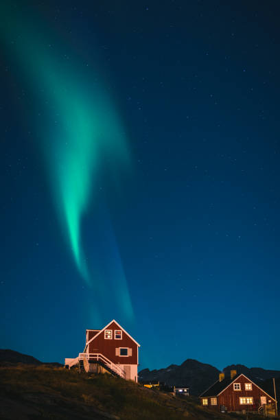 istock Green Aurora borealis over red houses 831833584