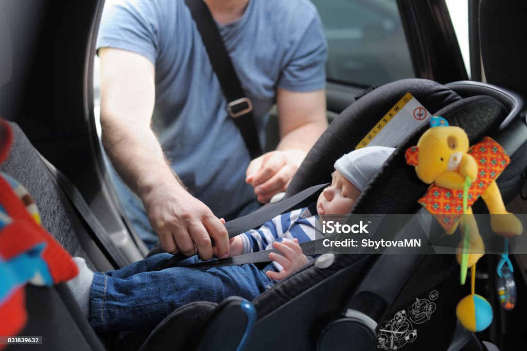 Father fasten his little son in car seat Father fasten his little son in car seat. The concept of security. Baby - Human Age Stock Photo