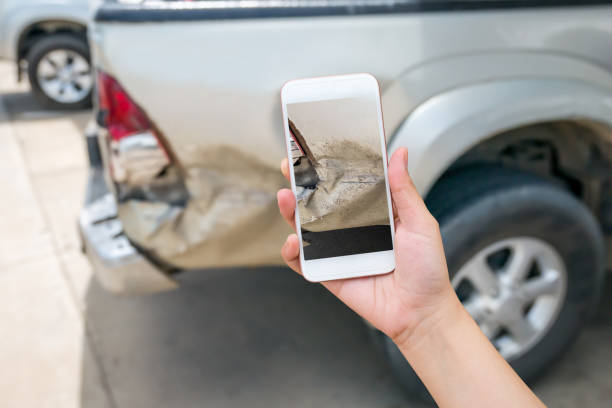 mujer utilizando teléfonos inteligentes para tomar fotos de daños de coche - accidente de automóvil fotos fotografías e imágenes de stock