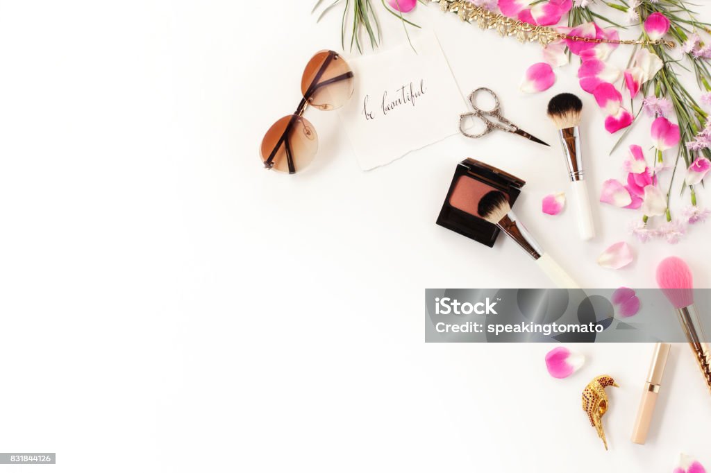 Top view of cosmetics and female accessories on white with pink petals. Beauty blog flat lay concept. Make-Up Stock Photo