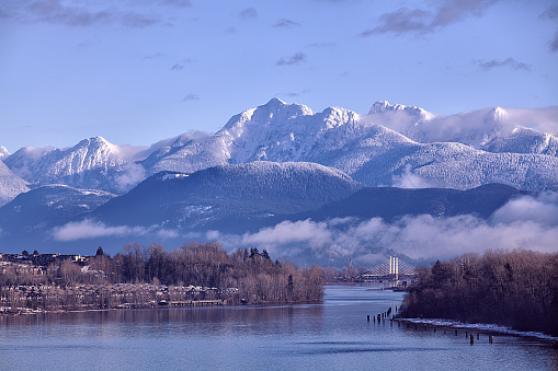Fraser river in the morning seen from Surrey in winter, mountains heavily covered with snow.