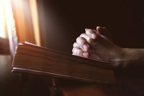 istock Hands Praying on Holy Bible beside a Window Light, Hope and Religion Concept 831873352