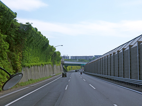 Driving by three lane highway in Tokyo, tall green Overgrown noise barriers with grass on roadsides, Japan