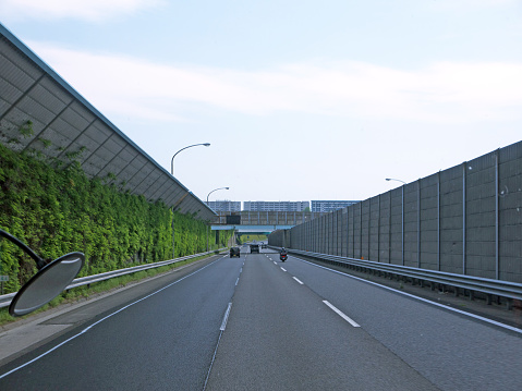 Driving by three lane highway in Tokyo, tall green Overgrown noise barriers with grass on roadsides, Japan