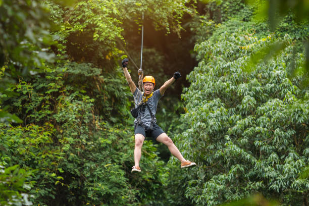 Freedom Man Tourist Wearing Casual Clothing On Zip Line Or Canopy Experience In Laos Rainforest, Asia Freedom Man Tourist Wearing Casual Clothing On Zip Line Or Canopy Experience In Laos Rainforest, Asia laos photos stock pictures, royalty-free photos & images