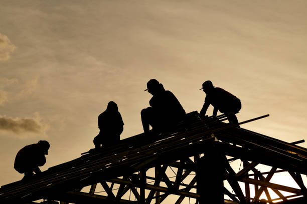 Georgetown, TX - 5 May 2025: Roofer installing shingles on roof of new home during thunderstorm and severe weather