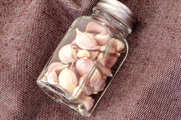 Close up the garlic in glass battle on brown fabric