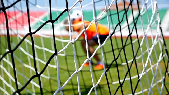 Slow motion of footballer soccer player training, football net in front