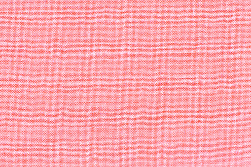Light pink background from a textile material with wicker pattern, closeup. Structure of the rose fabric with natural texture. Cloth backdrop.