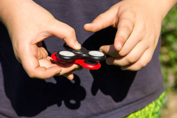 istock Boy playing with two fidget spinner stress relieving toys outdoor 831884992