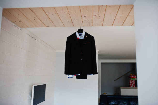 istock Groom's wedding suit hanging on the rack in big light room. 831895310