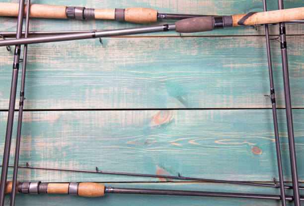 fishing theme. frame from fishing rods on green wooden background with free space inside. - pescaria com iscas artificiais imagens e fotografias de stock