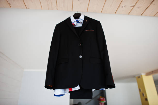 istock Groom's wedding suit hanging on the rack in big light room. 831896012