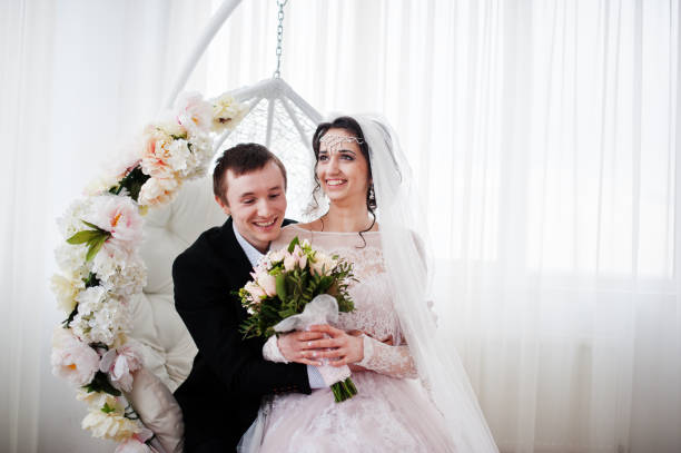 istock Wedding couple sitting on the floral swing in the studio. 831897036