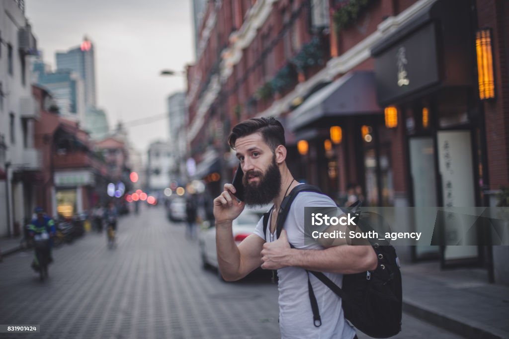 Handsome man on mobile One man, handsome and young with beard, outdoors in the city, talking on mobile phone. Adult Stock Photo