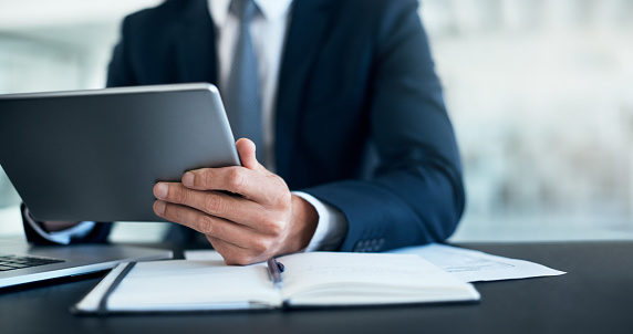 Cropped shot of a businessman using a digital tablet at his desk in a modern office