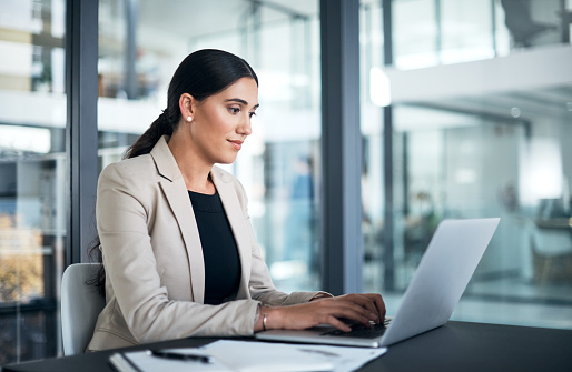 Shot of a businesswoman using a laptop at her desk in a modern office