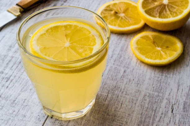 istock Lemon Liqueur Limoncello with lemon on white wooden surface. 831925012