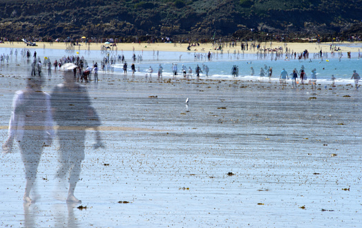 Le Sillon beach, St. Malo, Brittany, France. Les Malouins, as the inhabitants of St. Malo are known, and the many tourists enjoy a day on the beach. Merged image with blurred people.